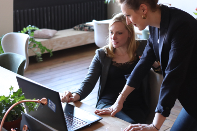 Two people reviewing information on a laptop